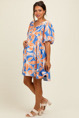 woman wearing a colorful floral print maternity dress with puff sleeves and a visible baby bump