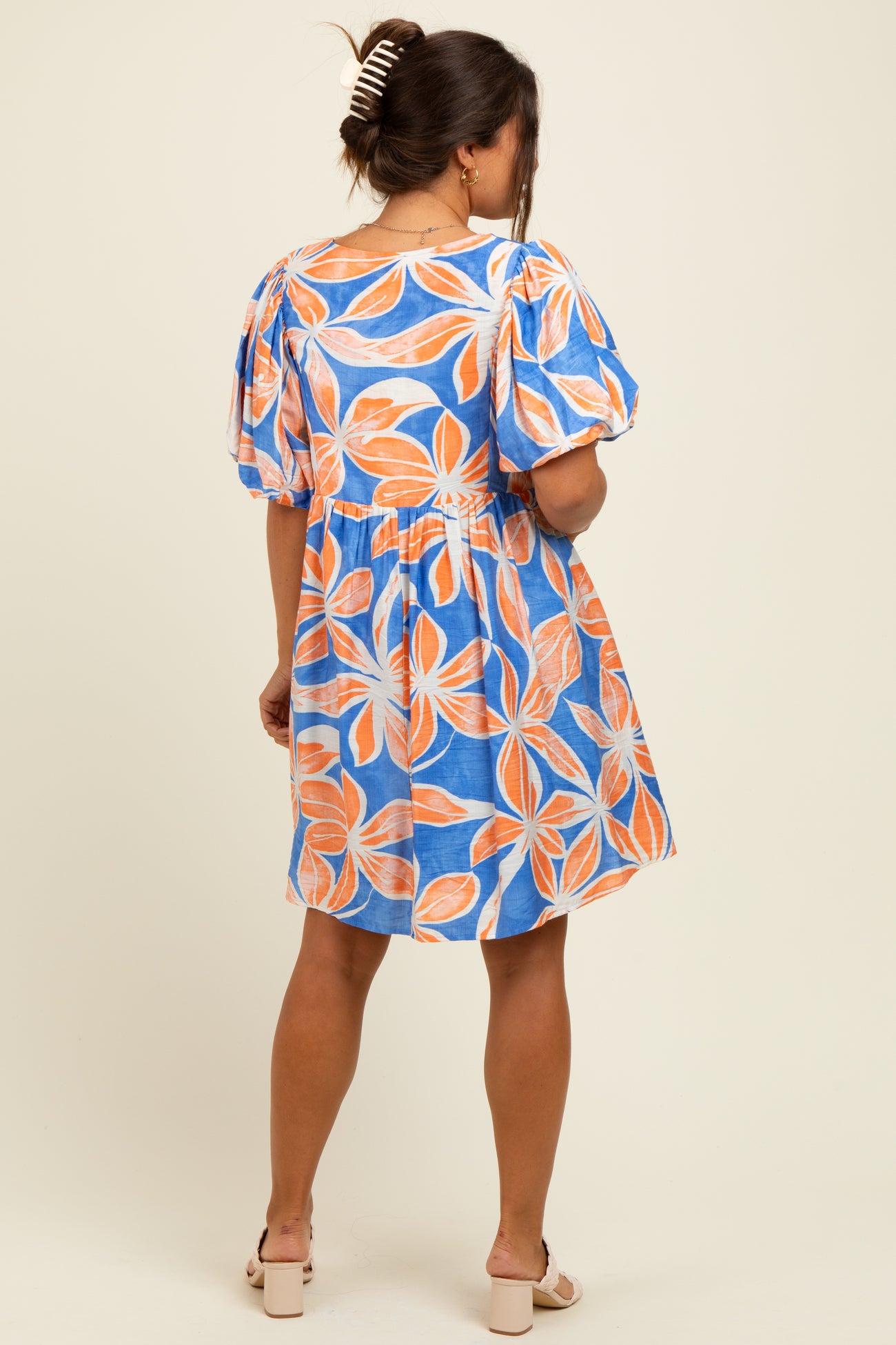 woman wearing a blue maternity dress with orange leaf prints and puff sleeves, showcasing a relaxed fit