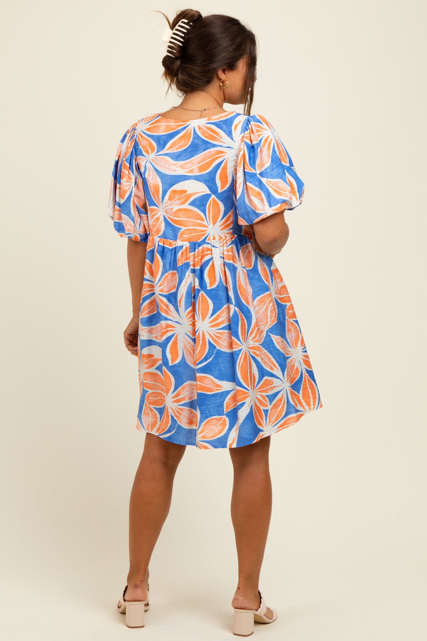 woman wearing a blue maternity dress with orange leaf prints and puff sleeves, showcasing a relaxed fit