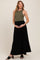 woman wearing a dark olive ribbed maternity tank top and a black maxi skirt, holding her baby bump