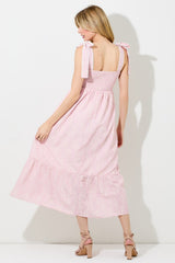 woman wearing a pink floral tie strap maxi dress, showing the back and ruffled hem detail