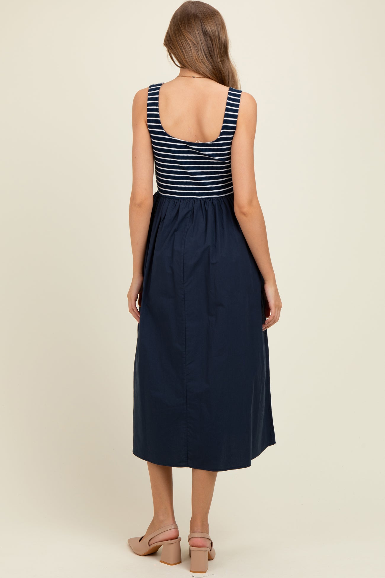 woman wearing a navy and white striped maternity dress with a fitted bodice and flowy skirt, showing a baby bump from behind
