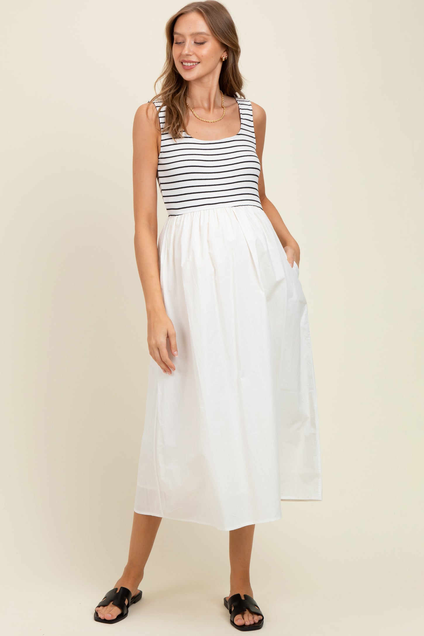 woman wearing a striped maternity dress with a white skirt and pockets, featuring a fitted bodice and flowing design