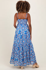 woman wearing a blue patterned maternity maxi dress with thin straps, showing a baby bump from the back