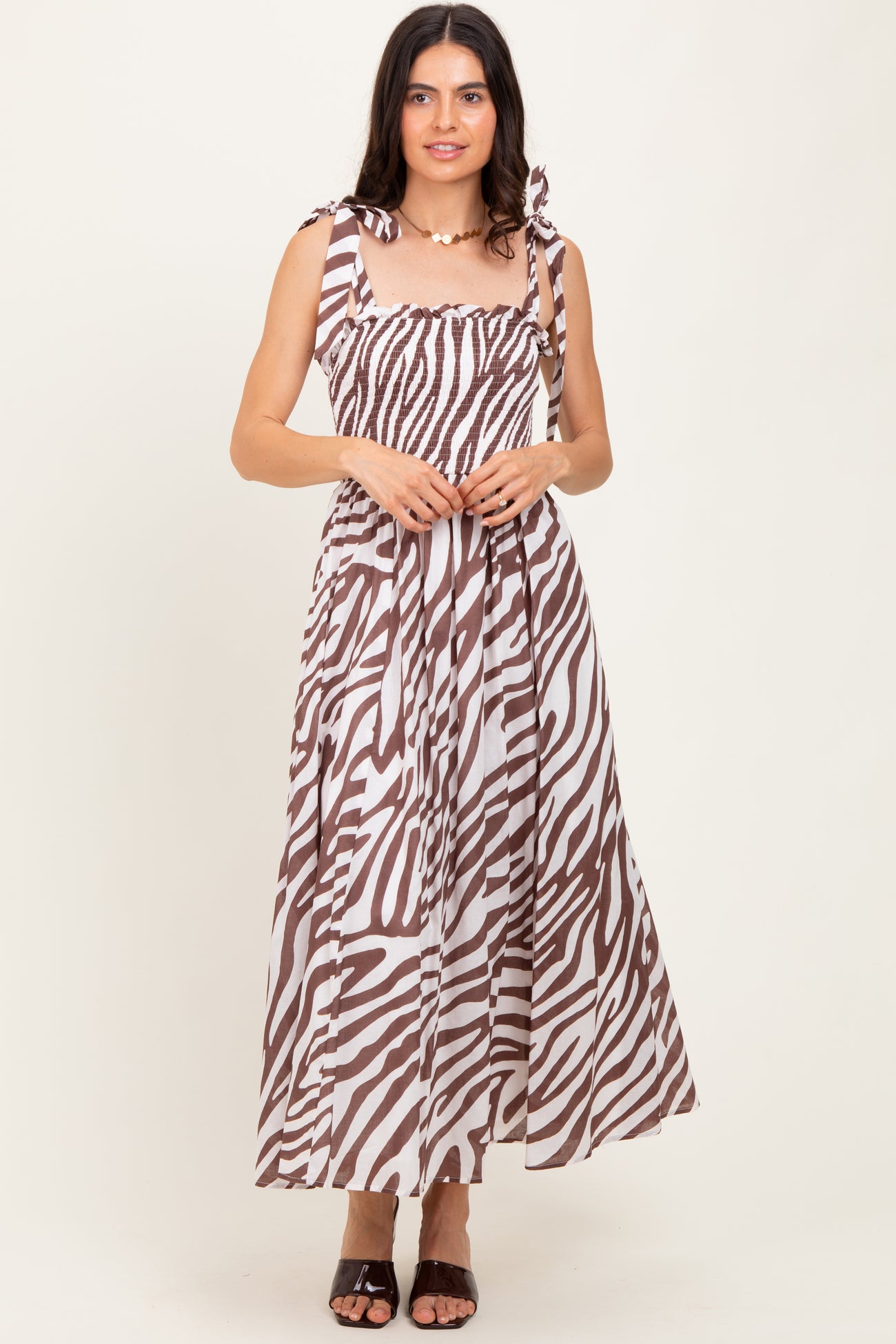 woman wearing a brown and white striped maxi dress with tie shoulder straps and a smocked bodice