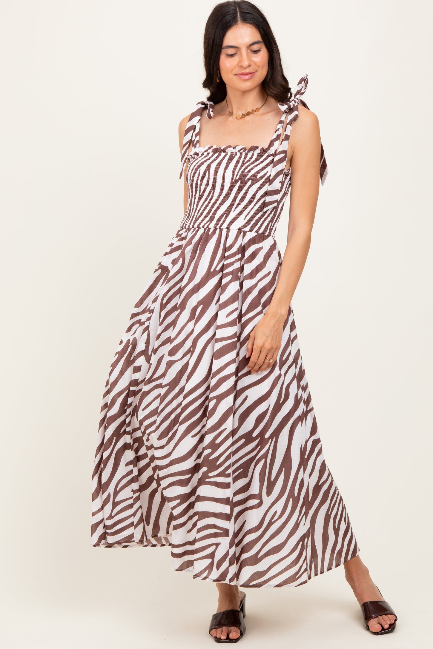 woman wearing a brown and white zebra print maxi dress with tie straps and a smocked bodice