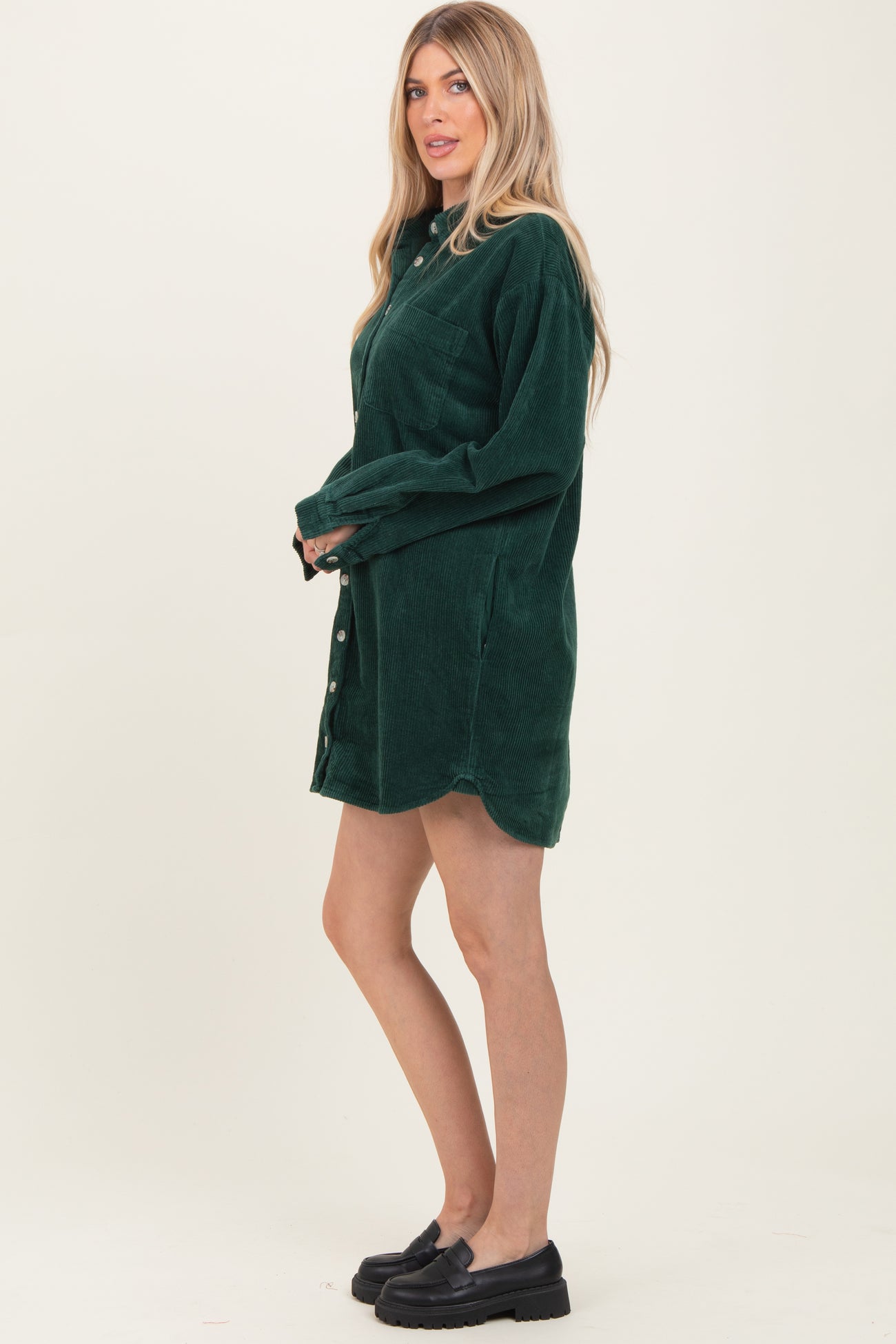 woman wearing a dark green corduroy shirt dress with a button-up front and long sleeves