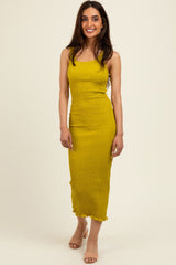 woman wearing a mustard yellow fitted midi dress with ruching and ruffle hem details