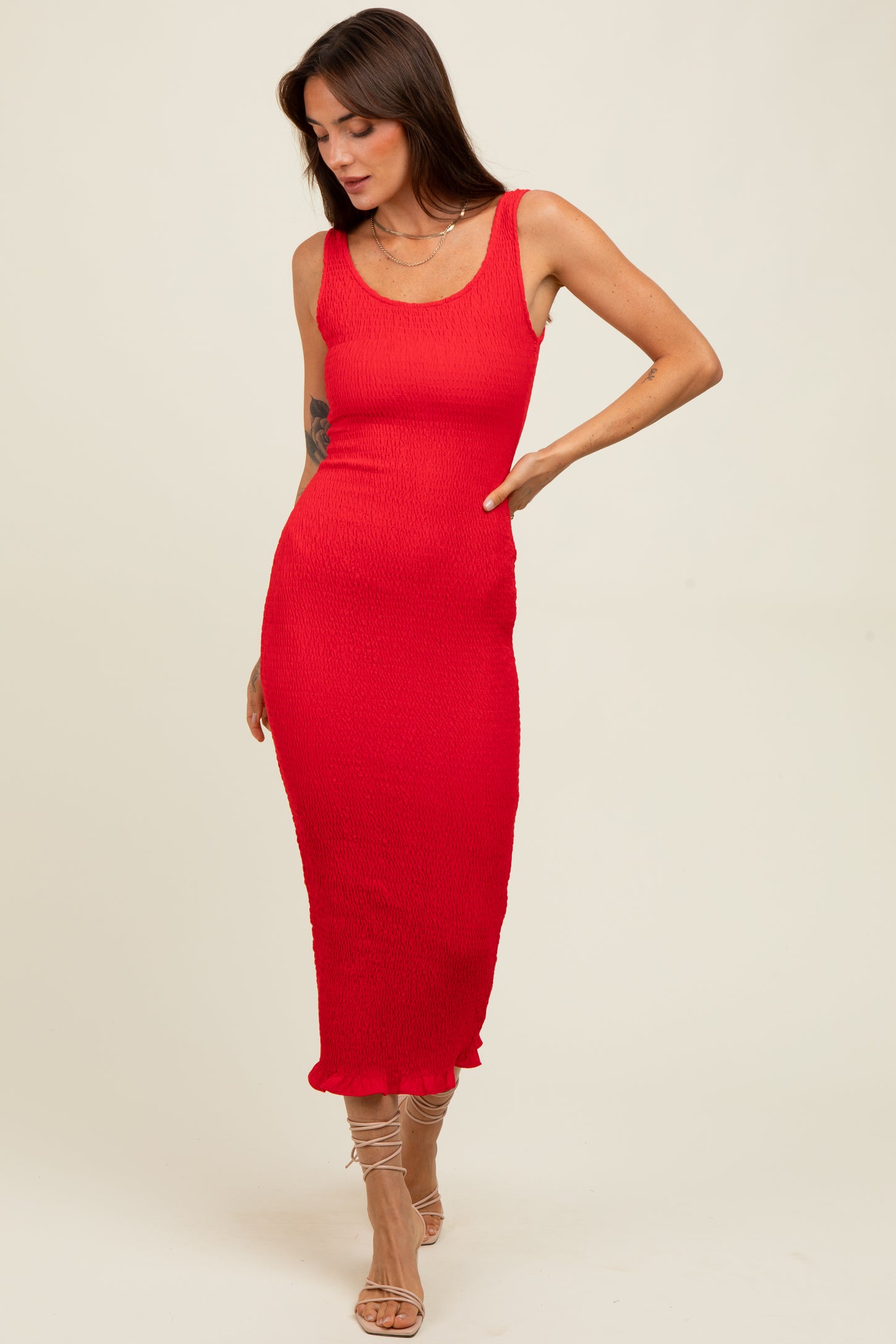 woman wearing a fitted red midi dress with a scoop neckline and ribbed texture, posing with her hand on her hip