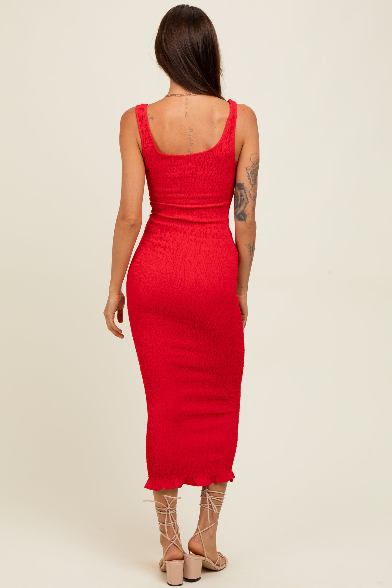 woman wearing a fitted red midi dress with a scoop neckline and ruffled hem, shown from the back