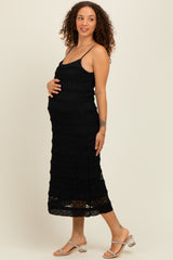 woman wearing a black ruffled maternity dress and holding her baby bump