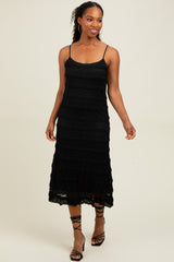 woman wearing a black tiered midi dress with spaghetti straps and strappy black heels