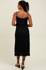 woman wearing a black lace midi dress with a fitted bodice and tiered skirt, viewed from the back
