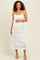 woman wearing a white lace maternity dress with adjustable straps and a visible baby bump