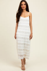 woman wearing a white lace maxi dress with a layered design and spaghetti straps, standing against a neutral background