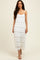 woman wearing a white lace maxi dress with a layered design and spaghetti straps, standing against a neutral background