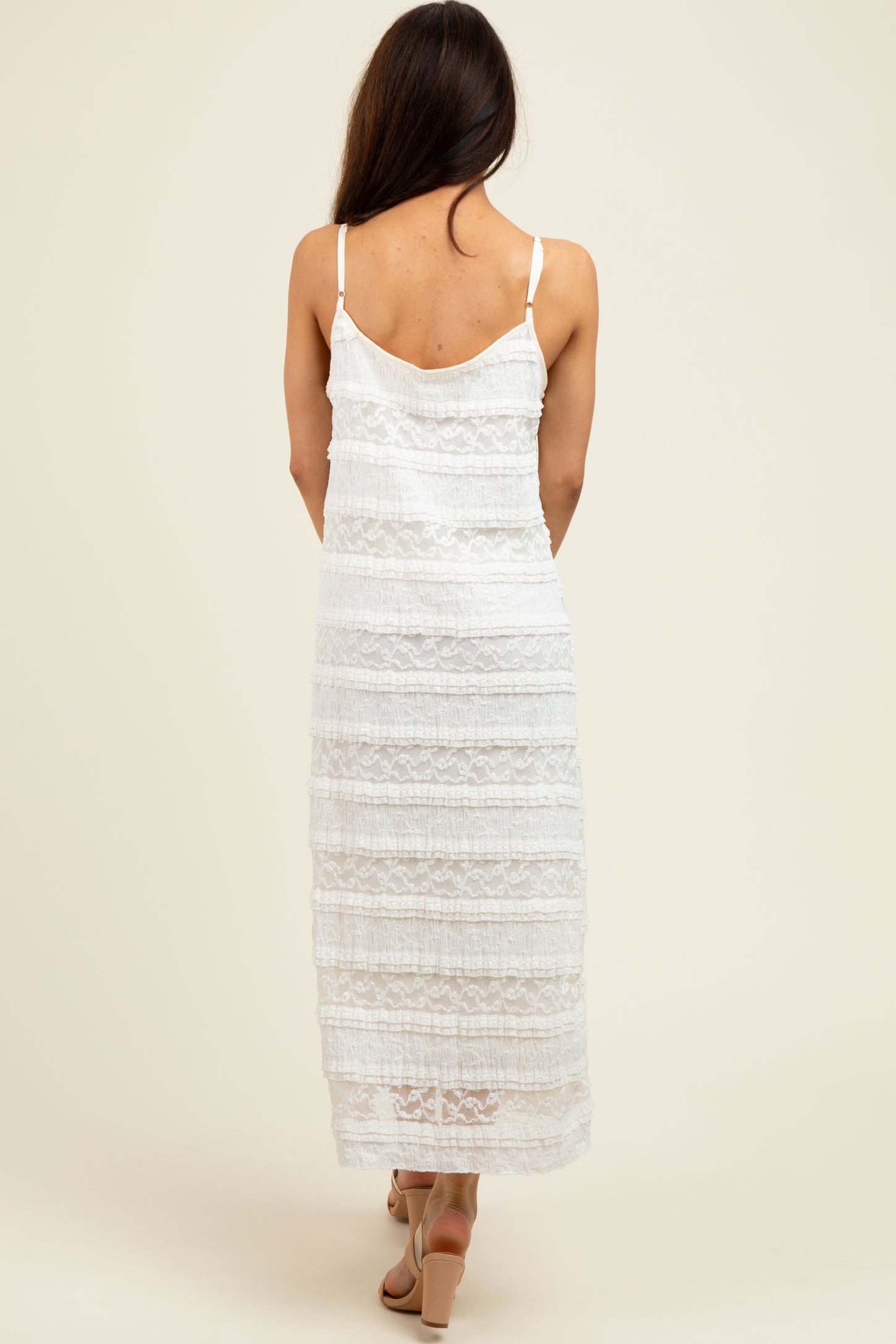 woman wearing a white lace maxi dress with a layered design and adjustable straps, viewed from the back