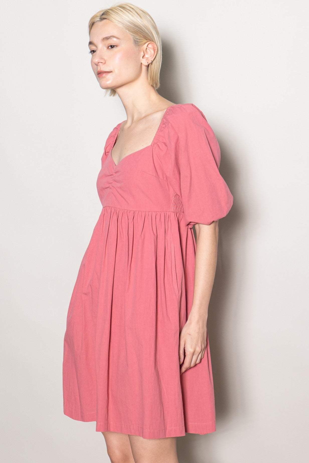 woman wearing a pink short puff sleeve dress with a square neckline and gathered detailing