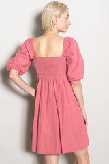 woman wearing a dusty pink puff sleeve mini dress with a square neckline and smocked back detail