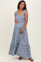 woman wearing a blue floral maternity maxi dress and holding her baby bump