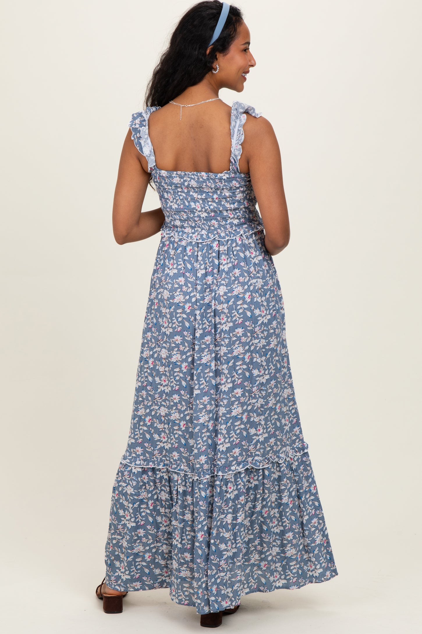 woman wearing a blue floral maternity maxi dress with ruffled straps and a flowy skirt, showing her back
