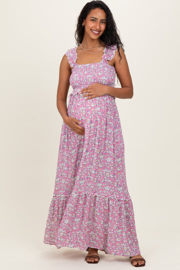 woman wearing a pink floral maternity maxi dress with ruffled straps and holding her baby bump