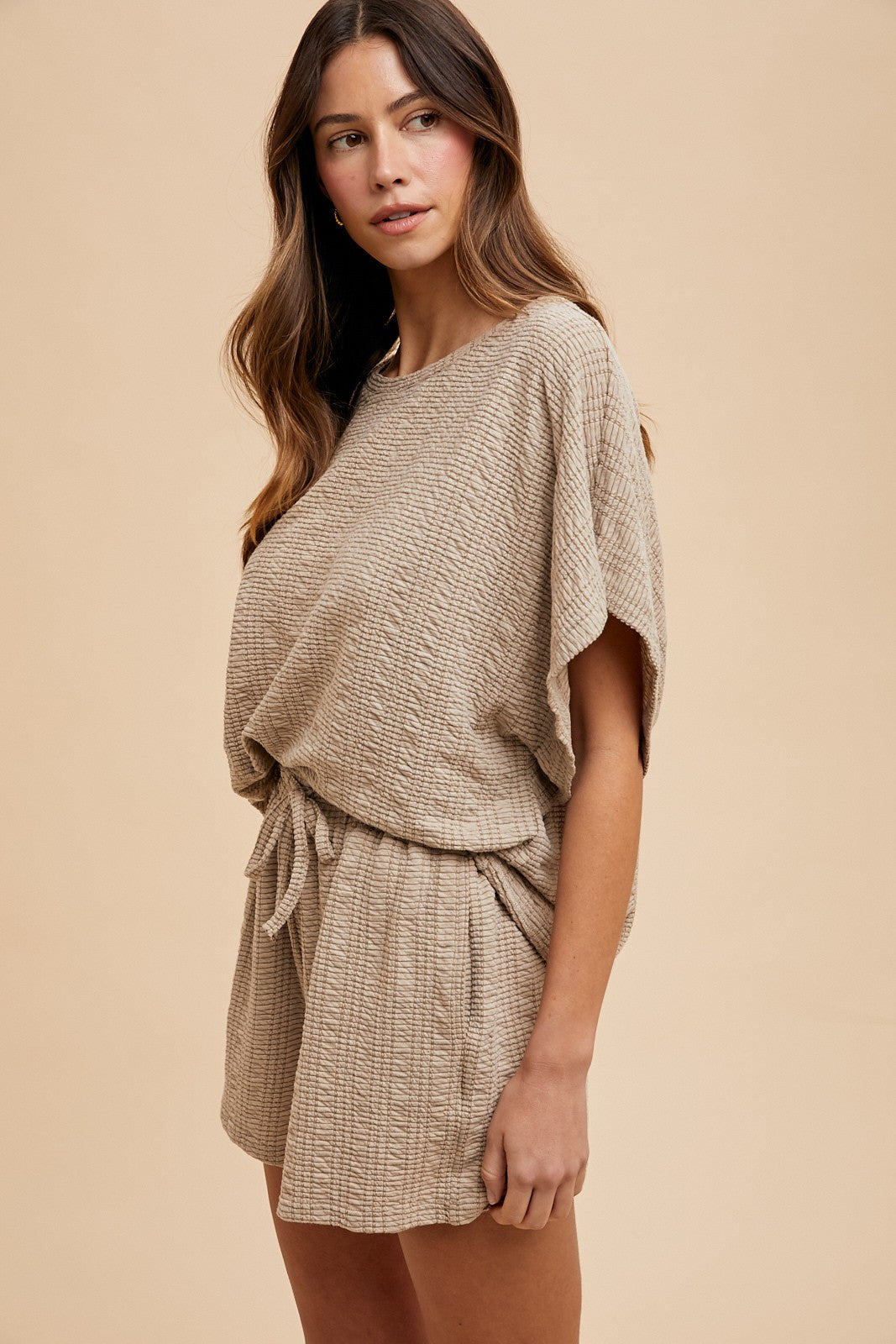 woman wearing a beige textured short set with a loose top and drawstring shorts