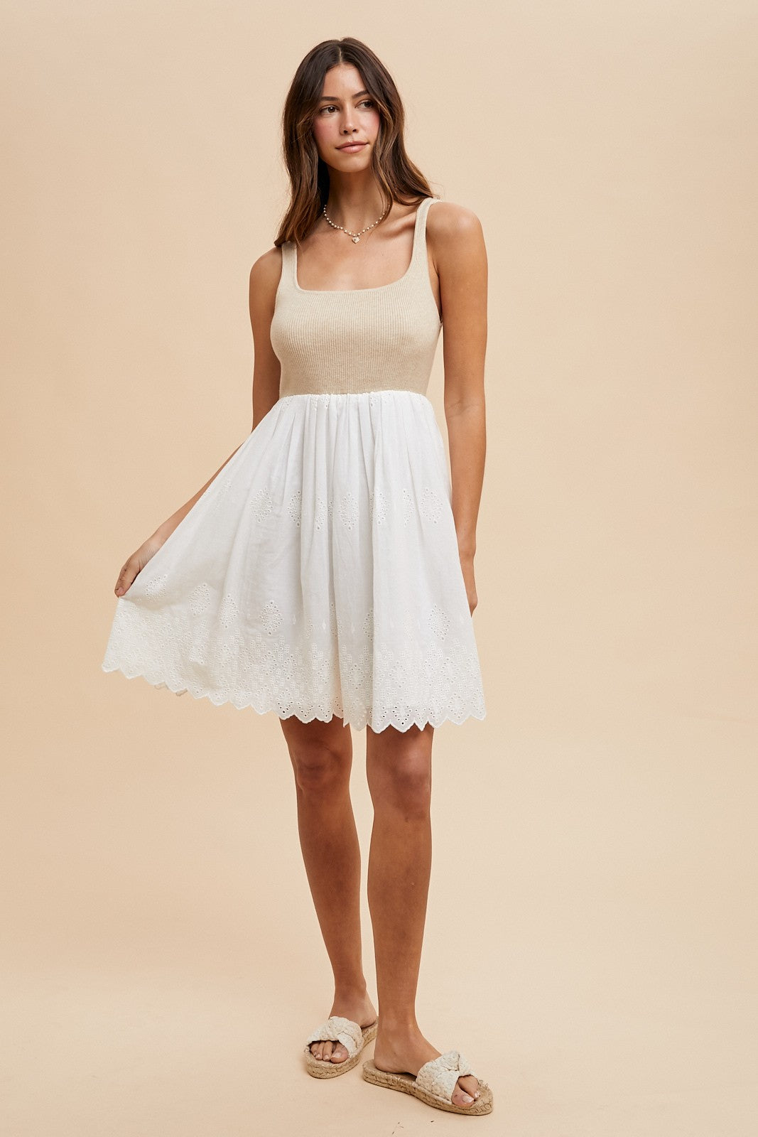 woman wearing a beige knit bodice sundress with a white embroidered skirt and white sandals