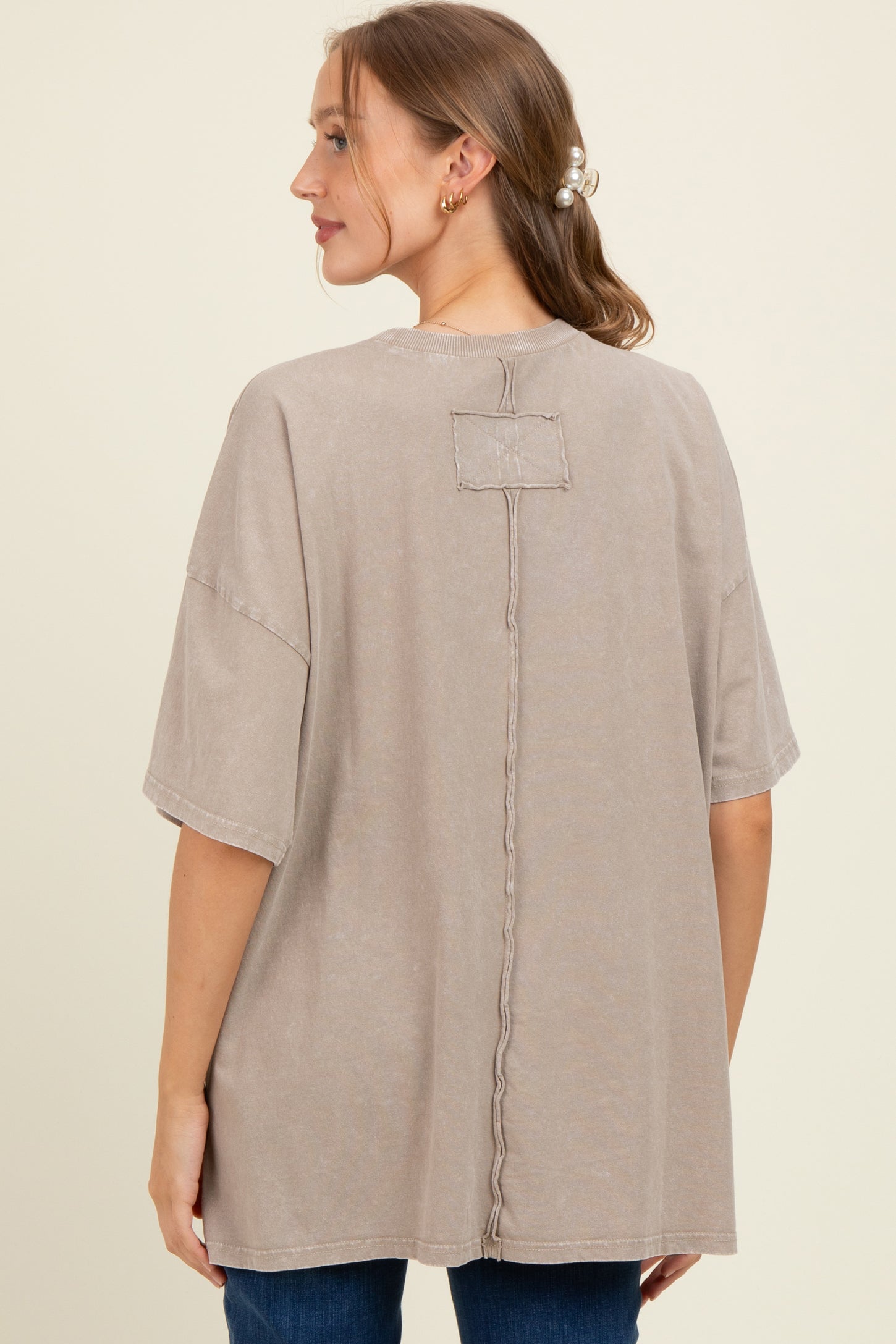 woman wearing a beige oversized maternity t-shirt with a stitched detail at the back