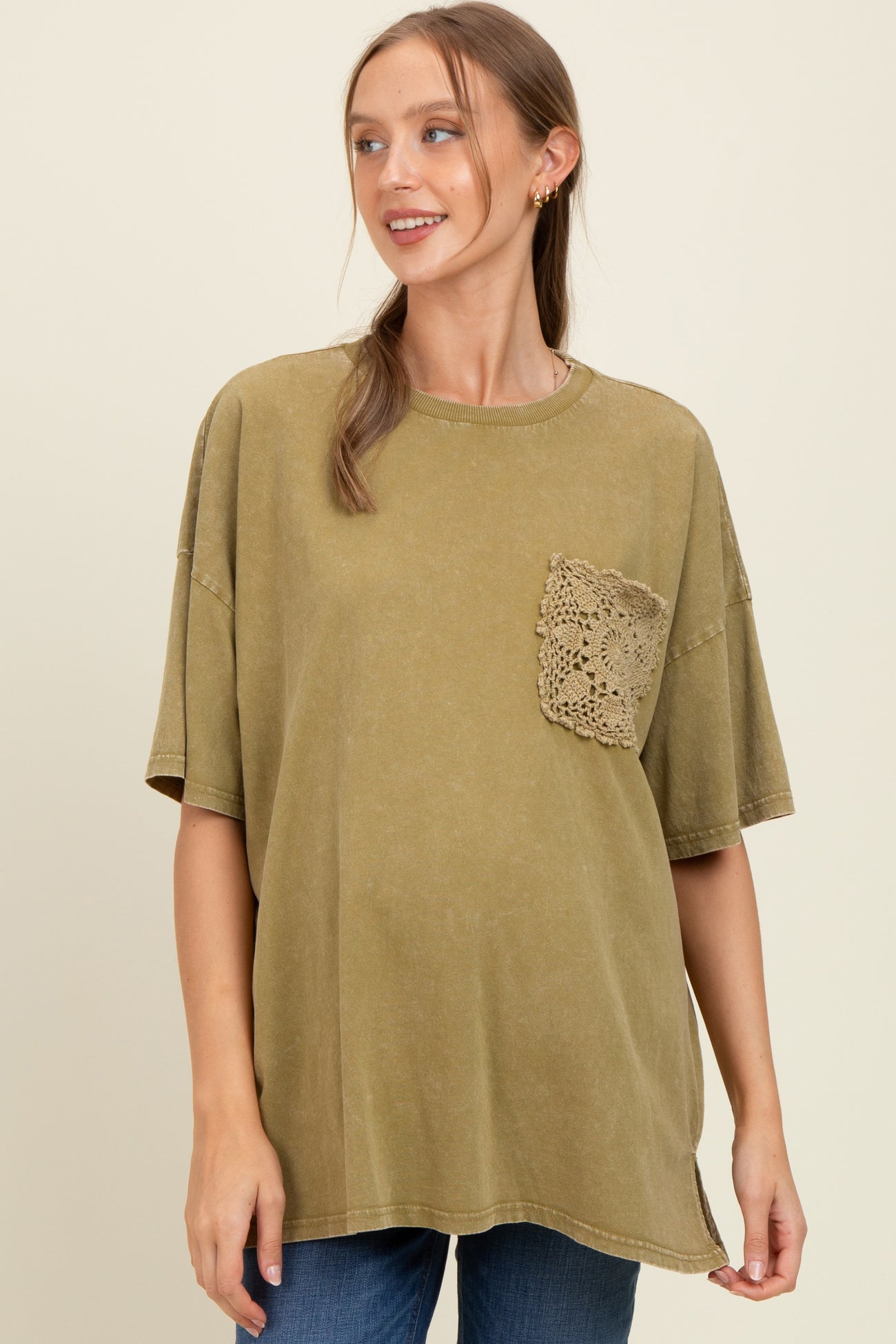 woman wearing an olive green oversized maternity t-shirt with a crochet pocket detail and a visible baby bump