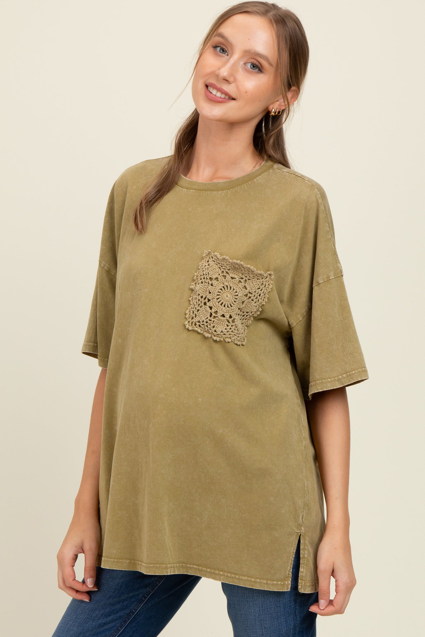 woman wearing a green oversized maternity t-shirt with a crochet pocket and side slits, showing her baby bump
