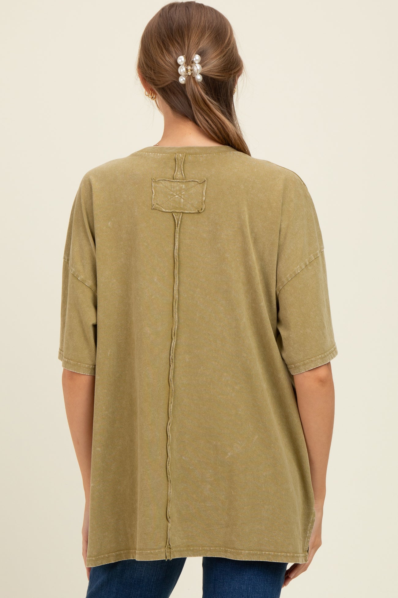 woman wearing an olive green oversized maternity t-shirt with a relaxed fit and a seam detail on the back