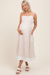woman wearing a light beige maternity dress with spaghetti straps and pockets, showing her baby bump