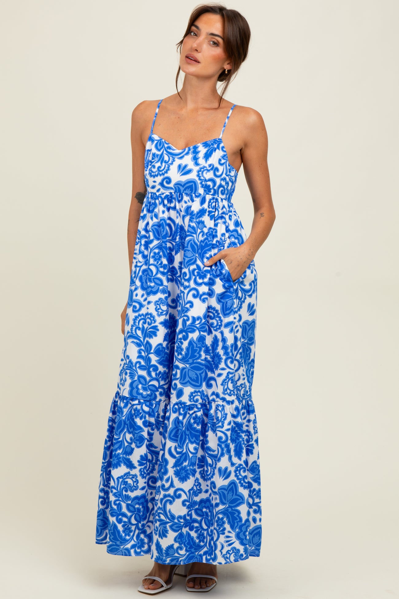 woman wearing a blue and white floral maxi dress with thin straps and pocket details