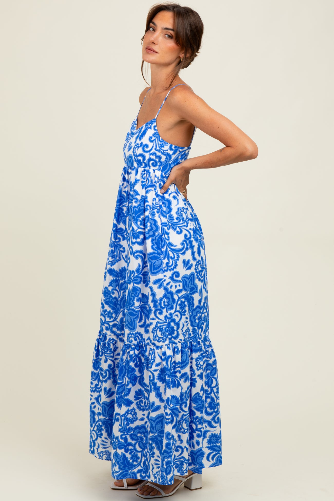 woman wearing a blue and white floral maxi dress with a tiered skirt and spaghetti straps
