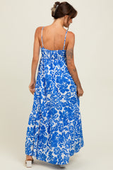 woman wearing a blue and white floral print maxi dress with thin straps and a tiered skirt, viewed from the back