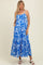 woman wearing a blue and white floral maternity maxi dress with pockets and adjustable straps, showing her baby bump