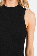 woman wearing a sleeveless black textured top with a high neckline