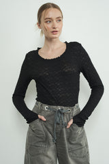 woman wearing a black lace long sleeve top with a scoop neckline and paired with gray drawstring cargo pants