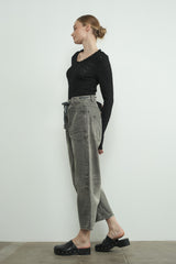 woman wearing a black long sleeve top and gray high-waisted baggy jeans with clogs