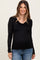 woman wearing a black long sleeve maternity top with a scalloped neckline and visible baby bump