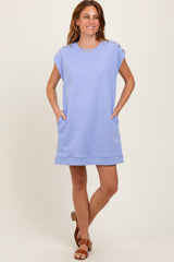 woman wearing a light purple oversized short sleeve dress with button details and side pockets