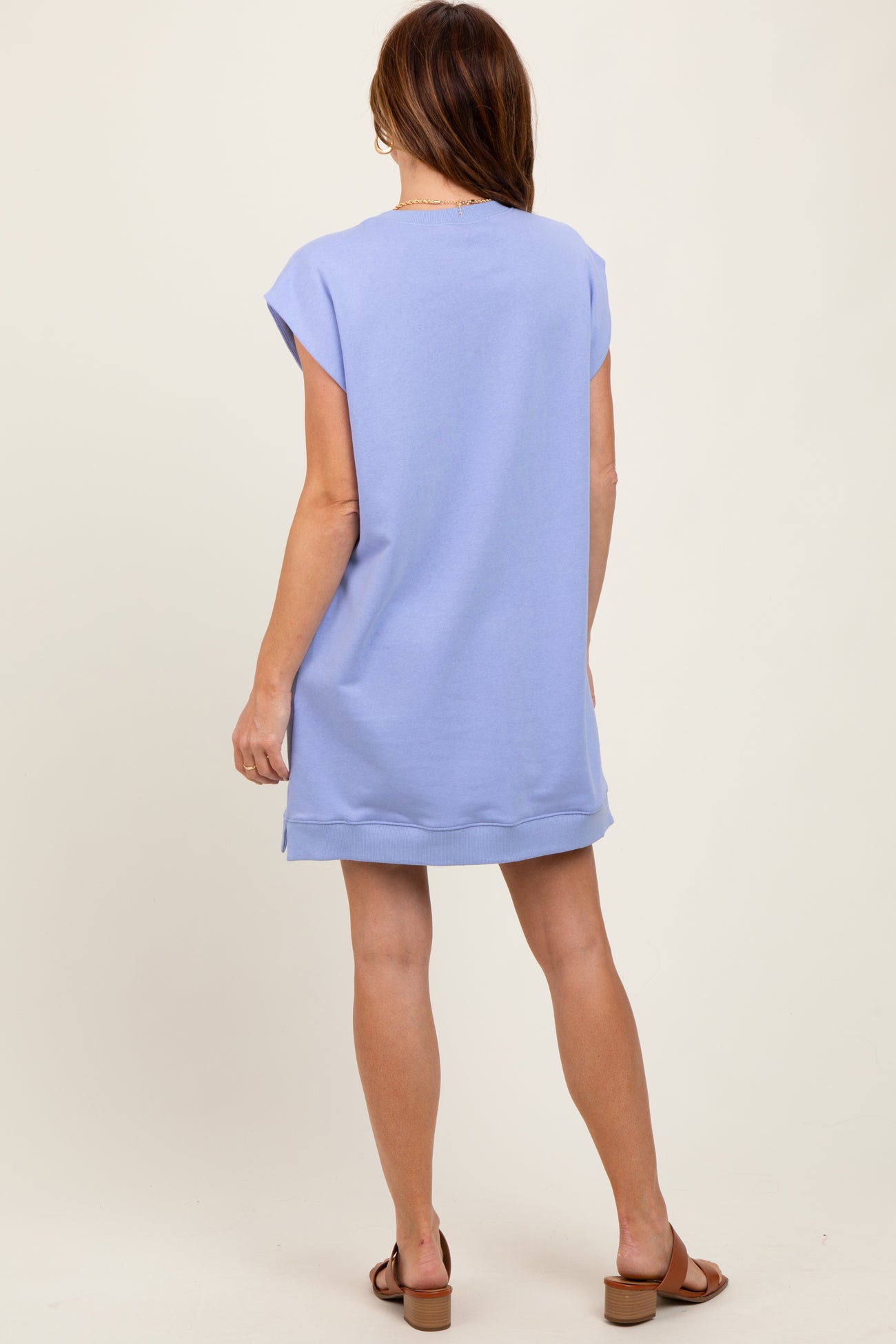 woman wearing a light blue oversized t-shirt dress, standing with her back to the camera, showcasing a relaxed fit