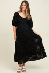 woman wearing a black floral lace maternity maxi dress with puff sleeves and a visible baby bump
