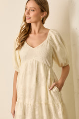 woman wearing a cream puff sleeve dress with floral embroidery and a v-neckline, styled with a relaxed fit and pockets