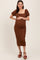 woman wearing a brown textured maternity dress with short puff sleeves and holding her baby bump