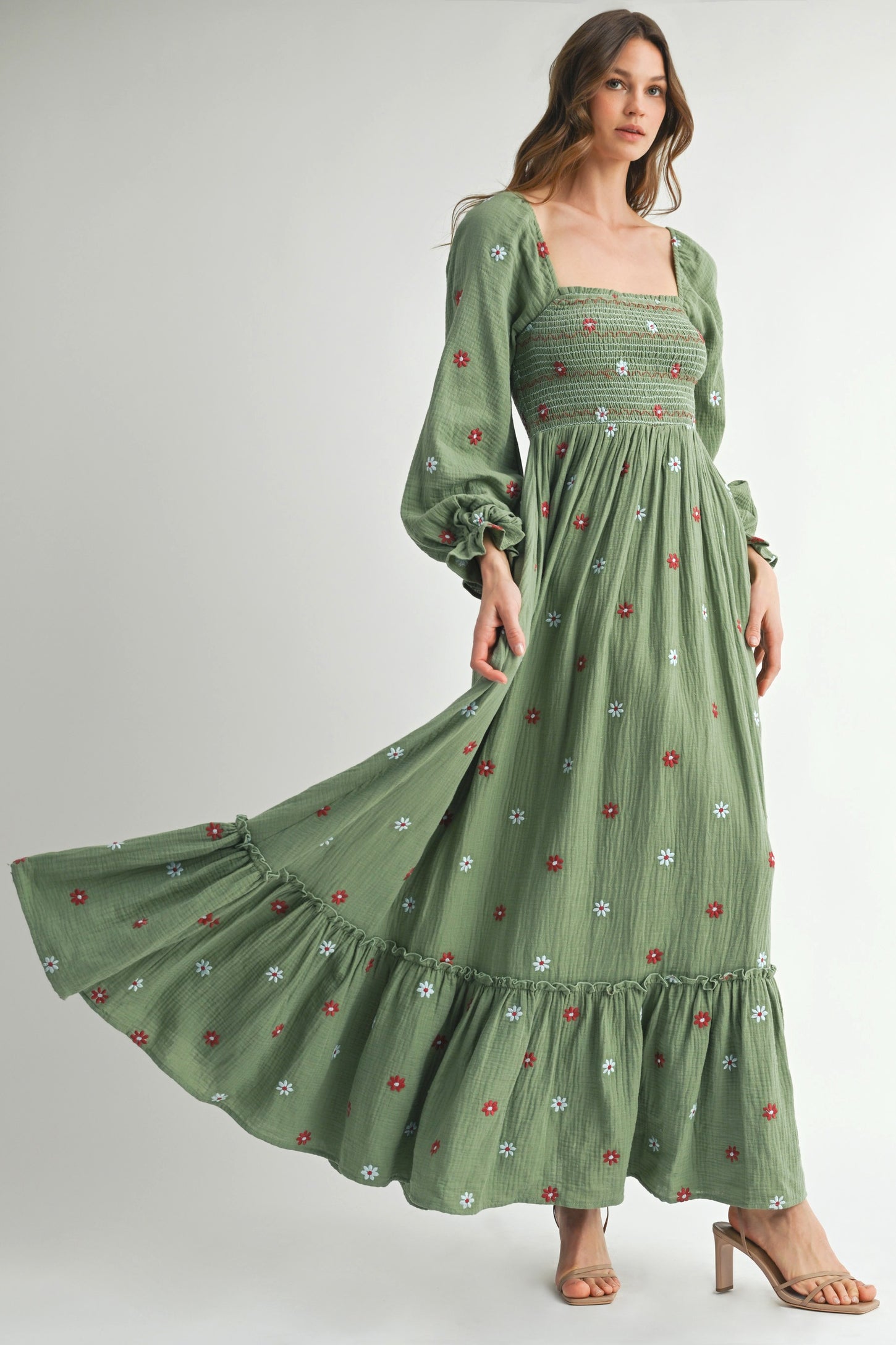woman wearing a green embroidered maxi dress with puff sleeves and floral details, twirling gracefully