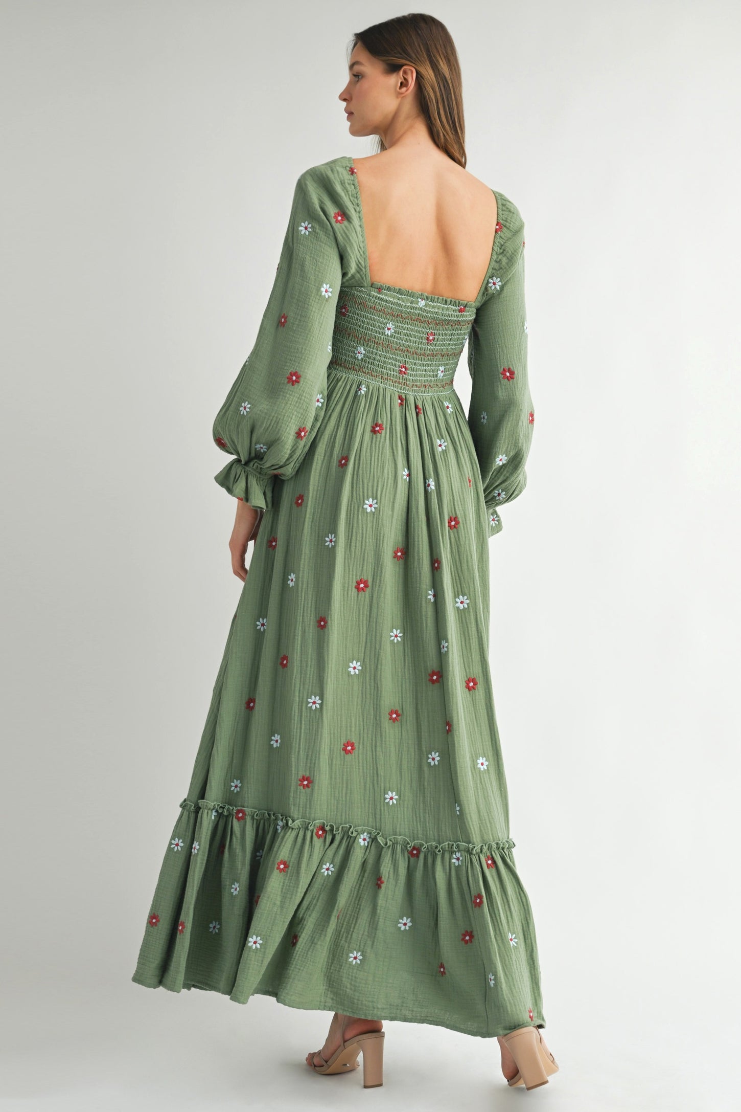 woman wearing a green long sleeve maxi dress with floral embroidery and a smocked back detail