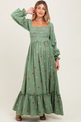 woman wearing a green floral embroidered maternity maxi dress with puff sleeves and ruffle hem