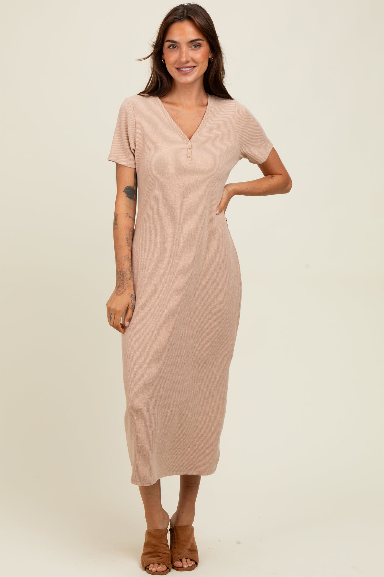 woman wearing a light beige short sleeve ribbed maxi dress with a v-neck and button details, standing and smiling